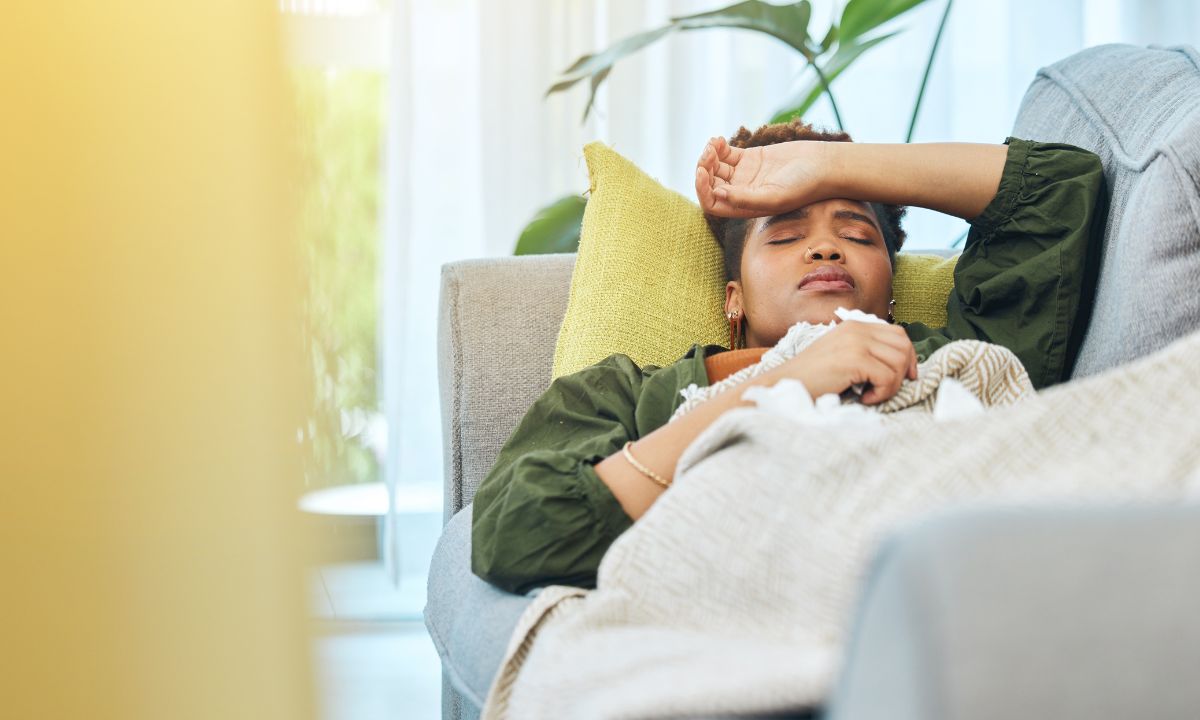 Kvinde ligger syg på sofaen.