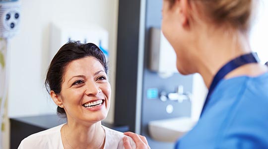 Patient og læge står og smiler til hinanden.