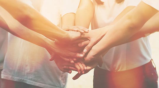 Billede af mange hænder som mødes i midten.