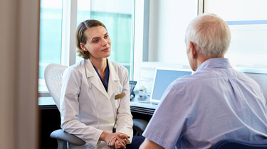 Patient og læge sidder under en konsultation.