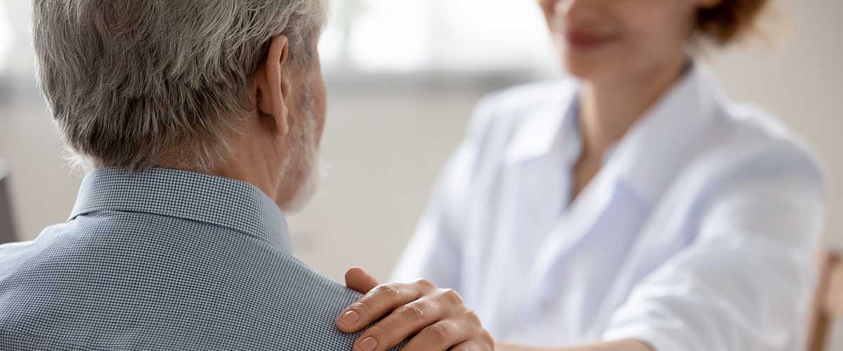 Læge holder på skulderen af en patient,