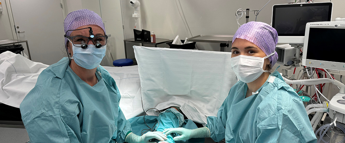 To kirurger med fuldt operationsudstyr kigger ind i kameraet.