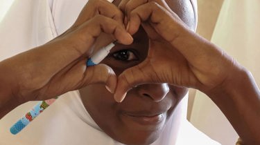 En kvinde former et hjerte med hænderne foran sit øje.