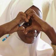 En kvinde former et hjerte med hænderne foran sit øje.