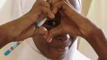 En kvinde former et hjerte med hænderne foran sit øje.