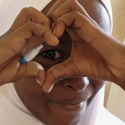 En kvinde former et hjerte med hænderne foran sit øje.