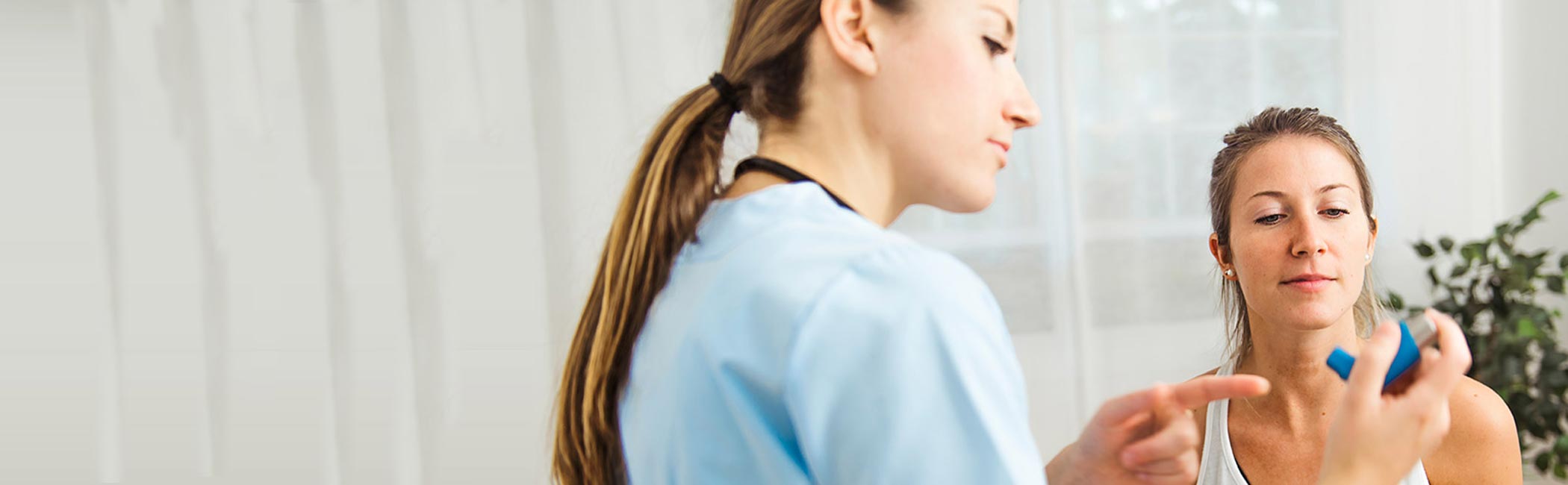 Læge rådgiver patient i, hvordan man bruger inhalator.