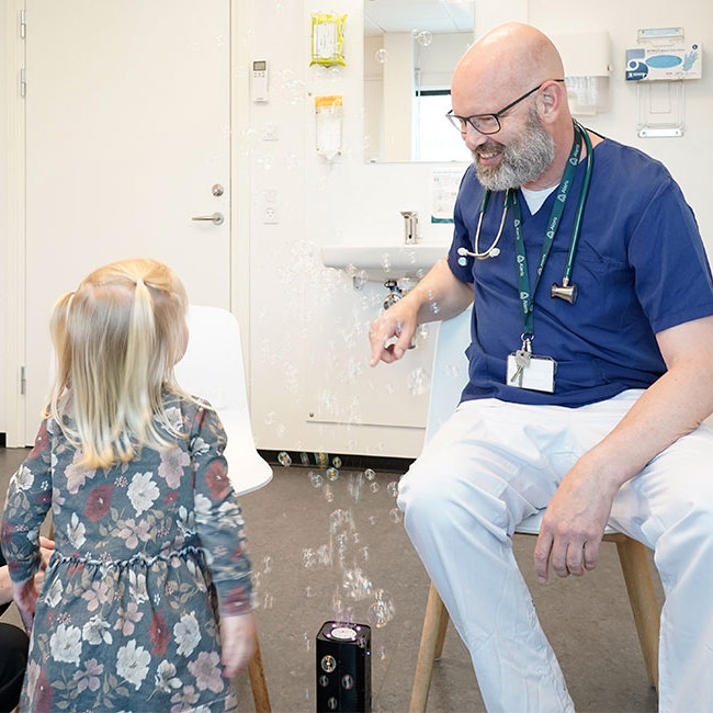 Børnelæge sammen med forældre og barn i en konsultation.