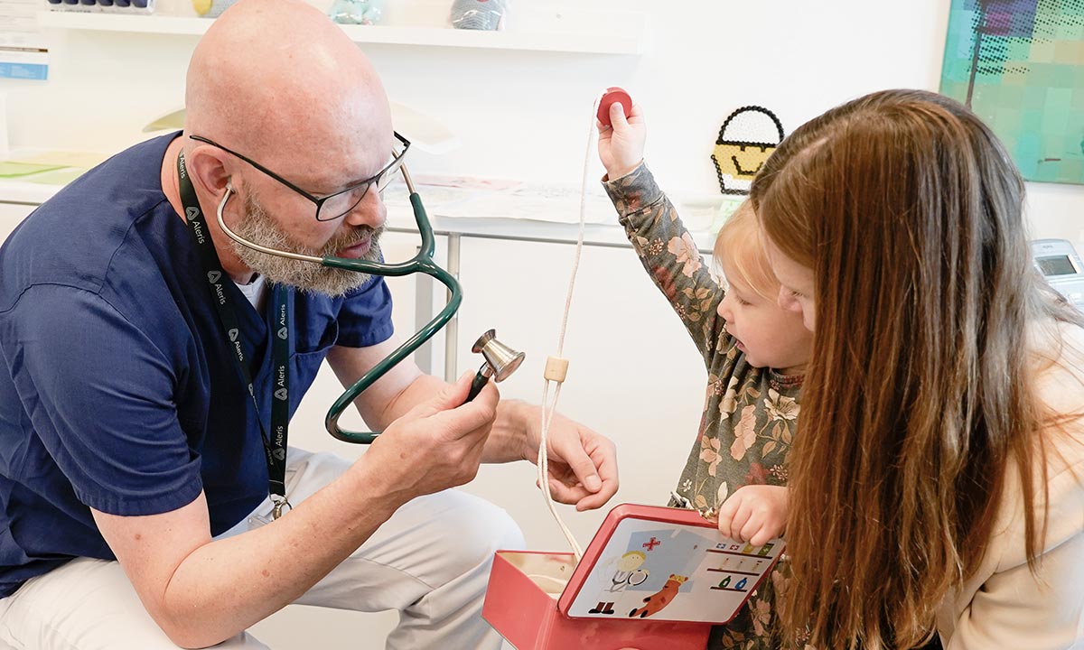 Børnelæge taler med mor og barn i konsultation omkring mavesmerter.