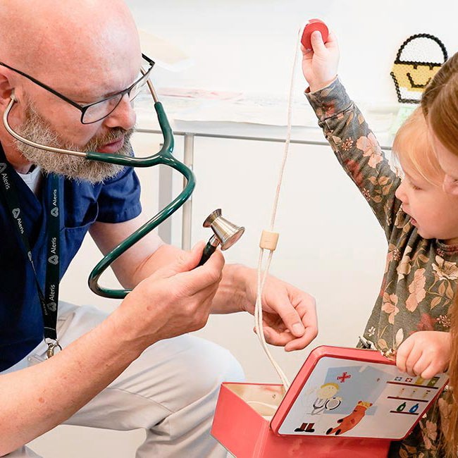 Børnelæge taler med mor og barn i konsultation omkring mavesmerter.