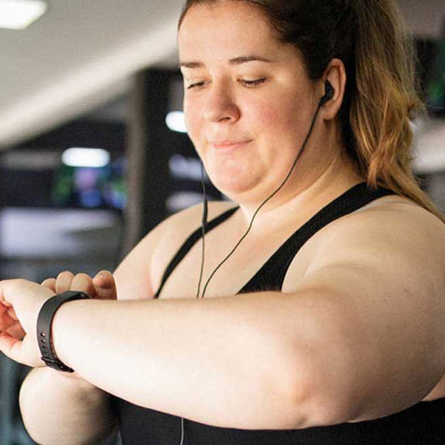 Overvægtig kvinde i fitnesscenter på løbebåndet.