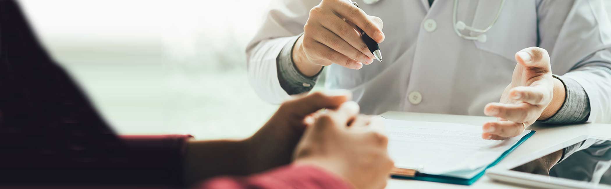 Læge skriver patient oplysninger ned under konsultation.