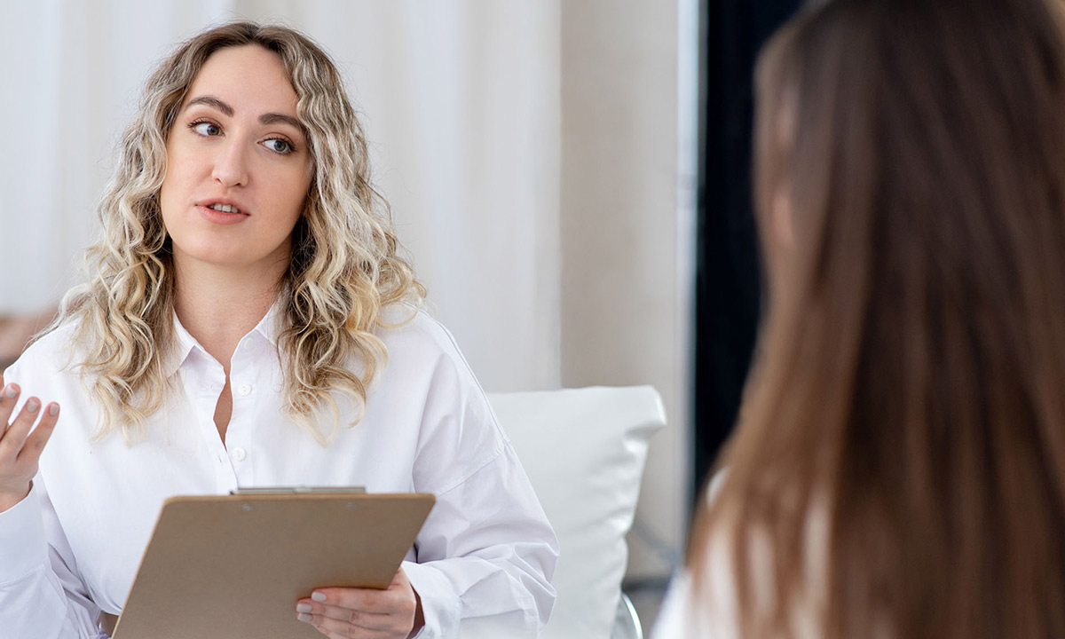 En kvindelig diætist sidder og taler med en klient.