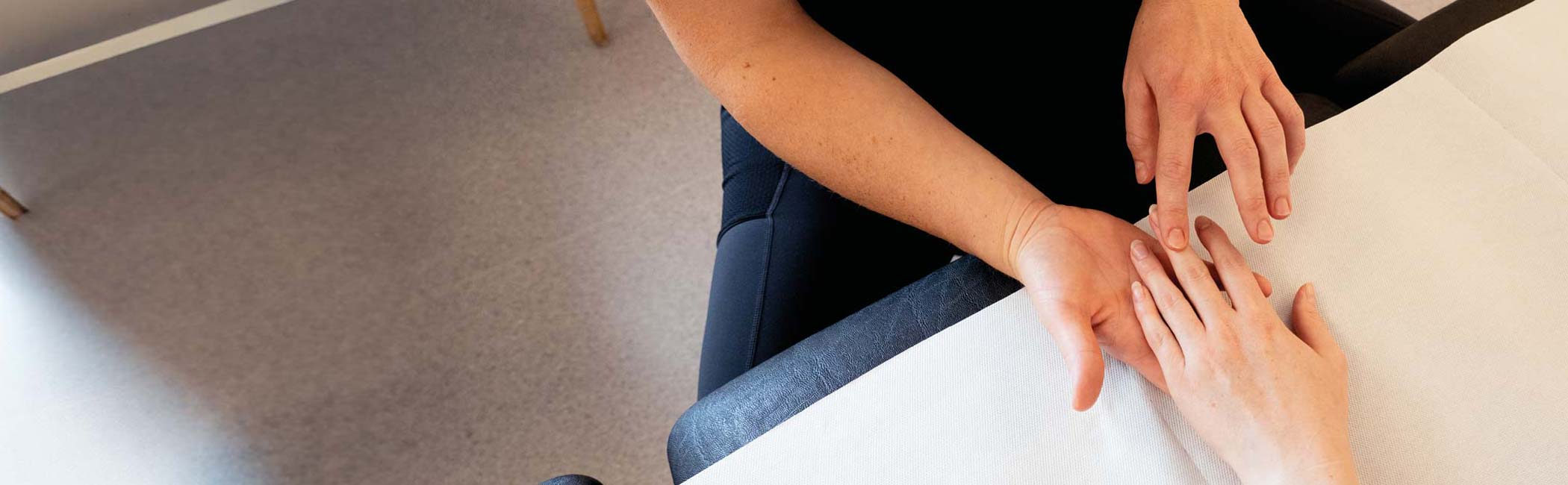 Fysioterapeut fra Aleris mærker patients mobilitet i hænder og fingre.