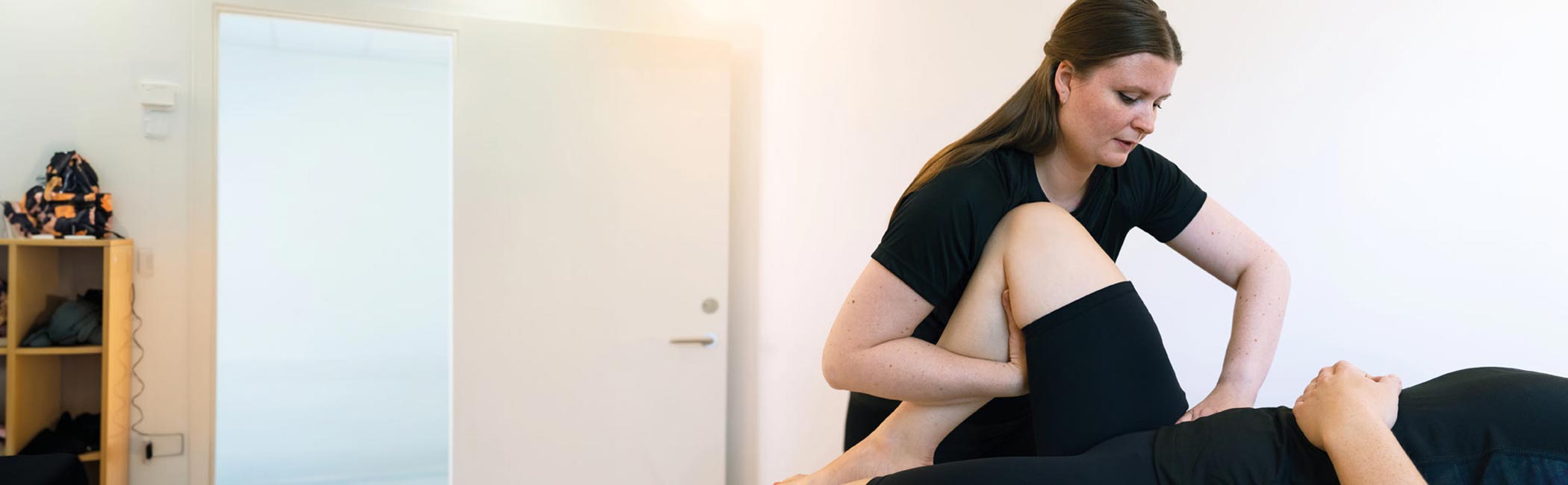 Fysioterapeut fra Aleris laver øvelser med patients lår.