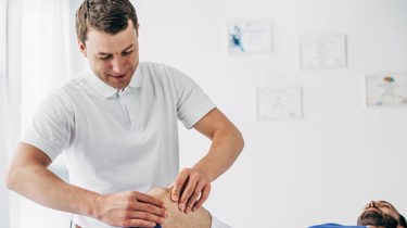 Fysioterapeut masserer patient på knæet.