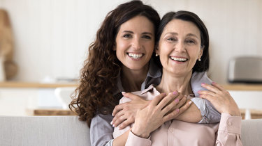 Datter holder om mor, og de smiler begge ind i kameraet.