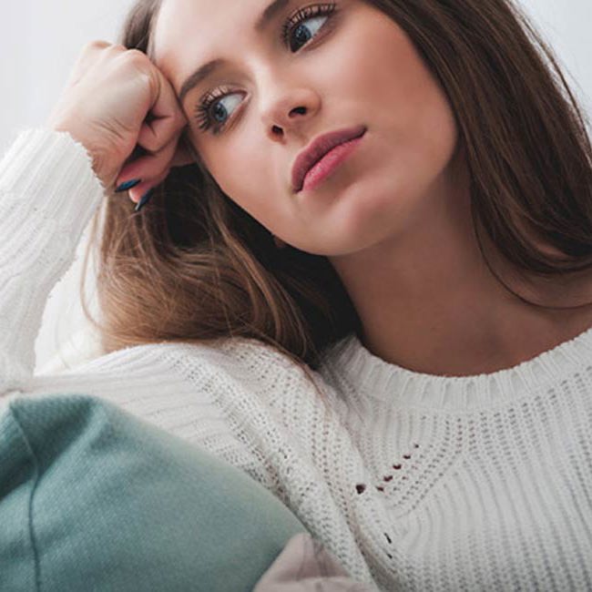 Kvinde sidder tænkende og kigger.