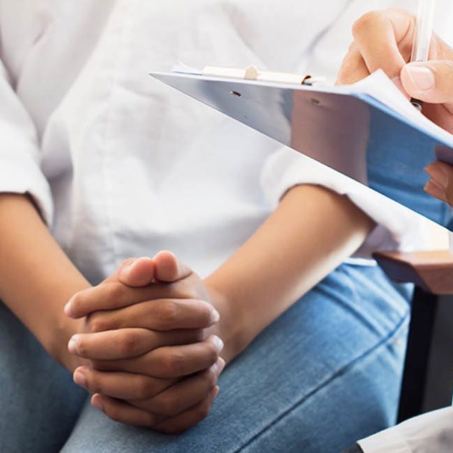 Kvinde sidder hos lægen.