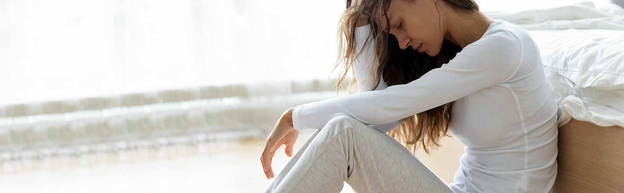 En kvinde sidder udmattet efter mange smerter i underlivet.