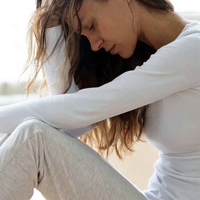 En kvinde sidder udmattet efter mange smerter i underlivet.