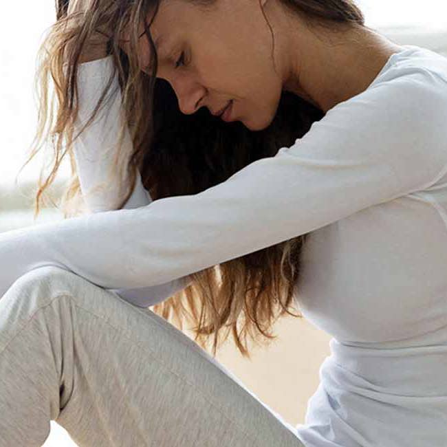 En kvinde sidder udmattet efter mange smerter i underlivet.