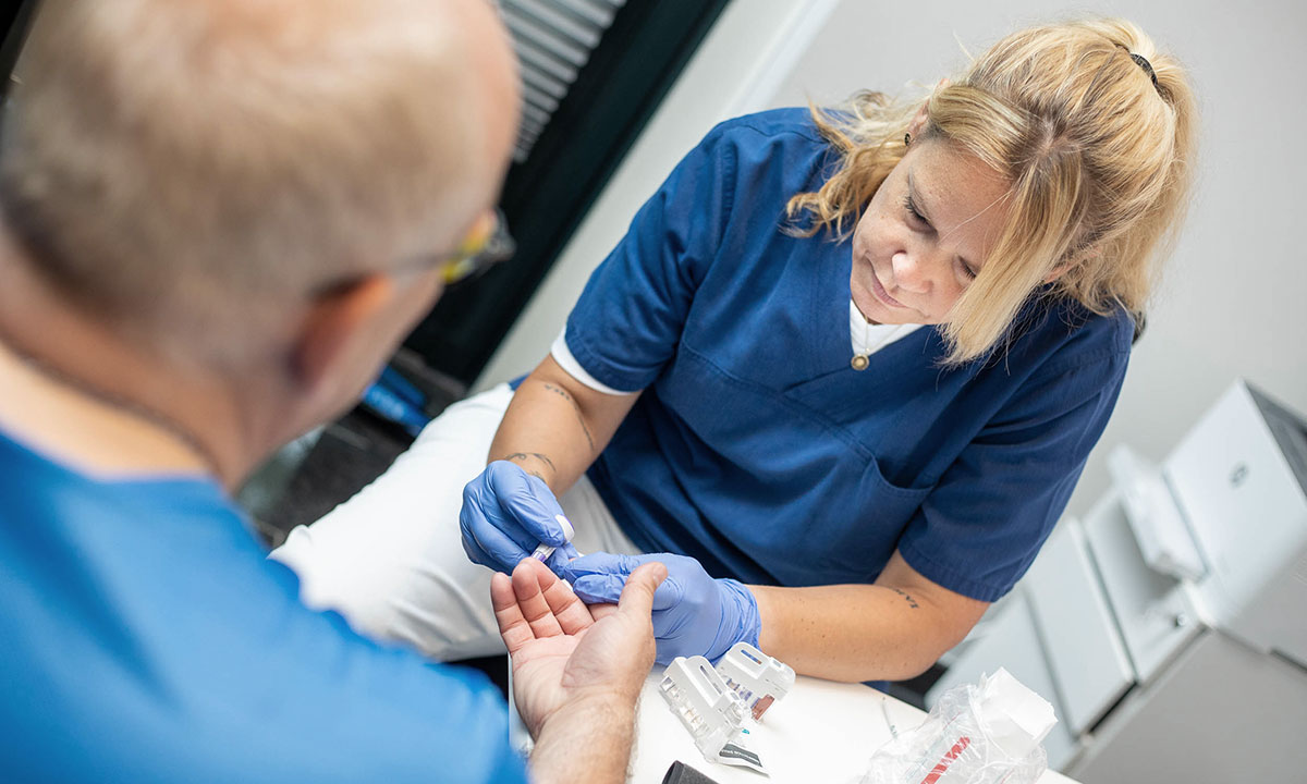 Sygeplejerske måler blodsukker under en helbredsundersøgelse hos Aleris.