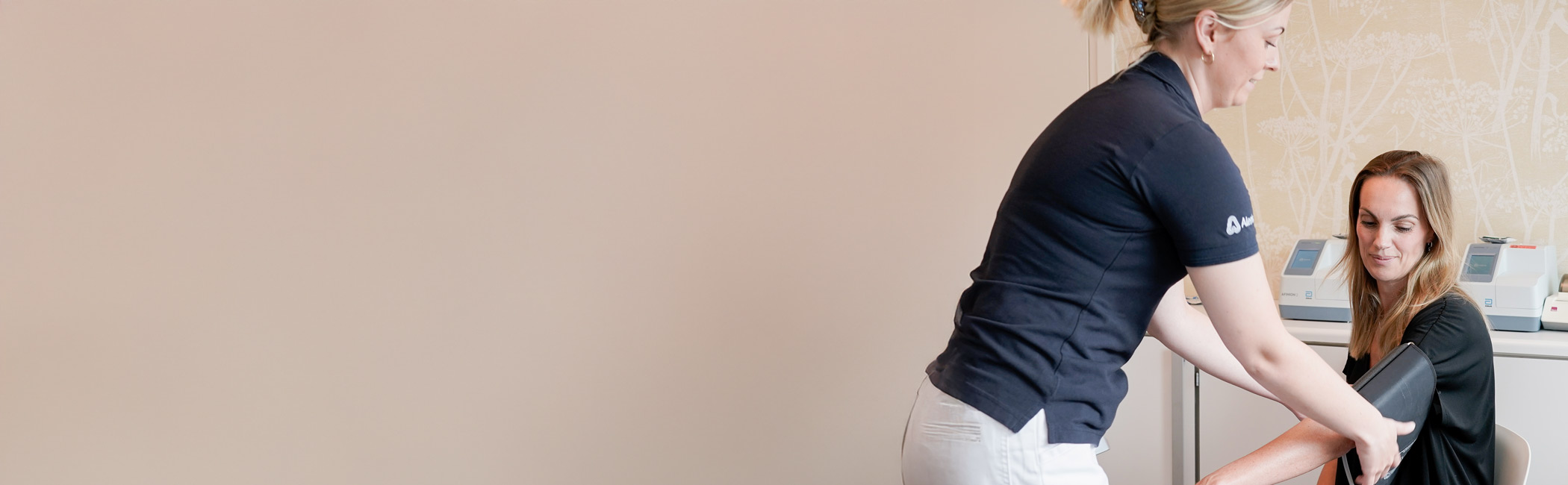 Helbredssygeplejerske måler blodtryk på patient.