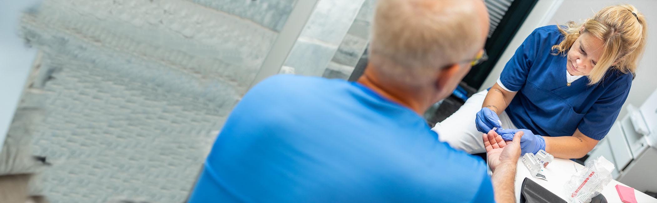 Sygeplejerske måler blodsukker under en helbredsundersøgelse hos Aleris.