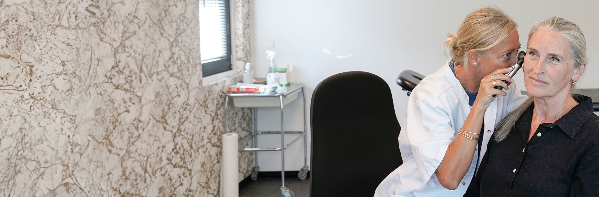 Helbredslæger undersøger ørerne på en patient.