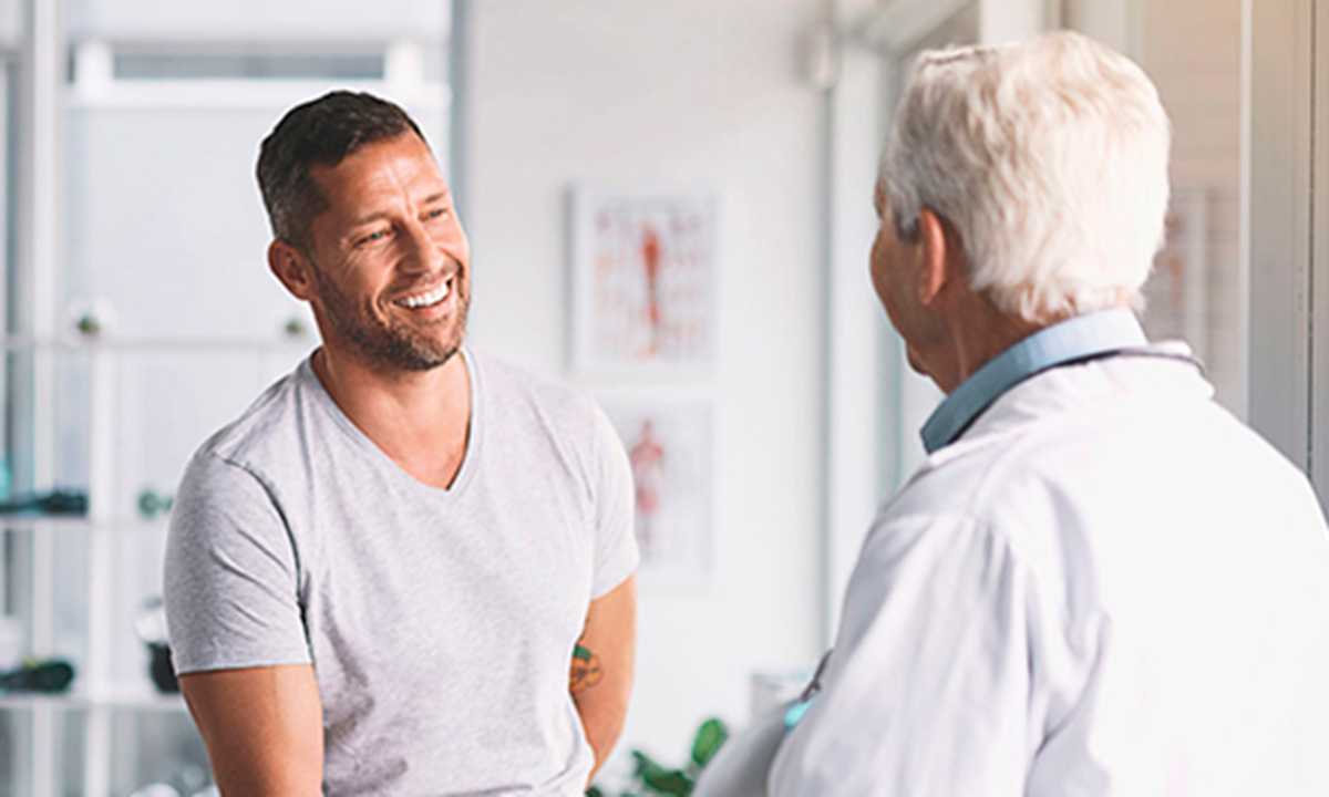 Læge taler med yngre mandlig patient til en konsultation.