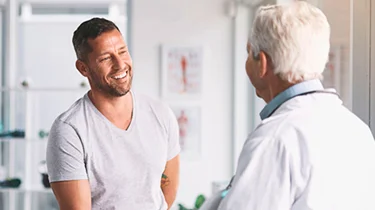 Læge taler med yngre mandlig patient til en konsultation.