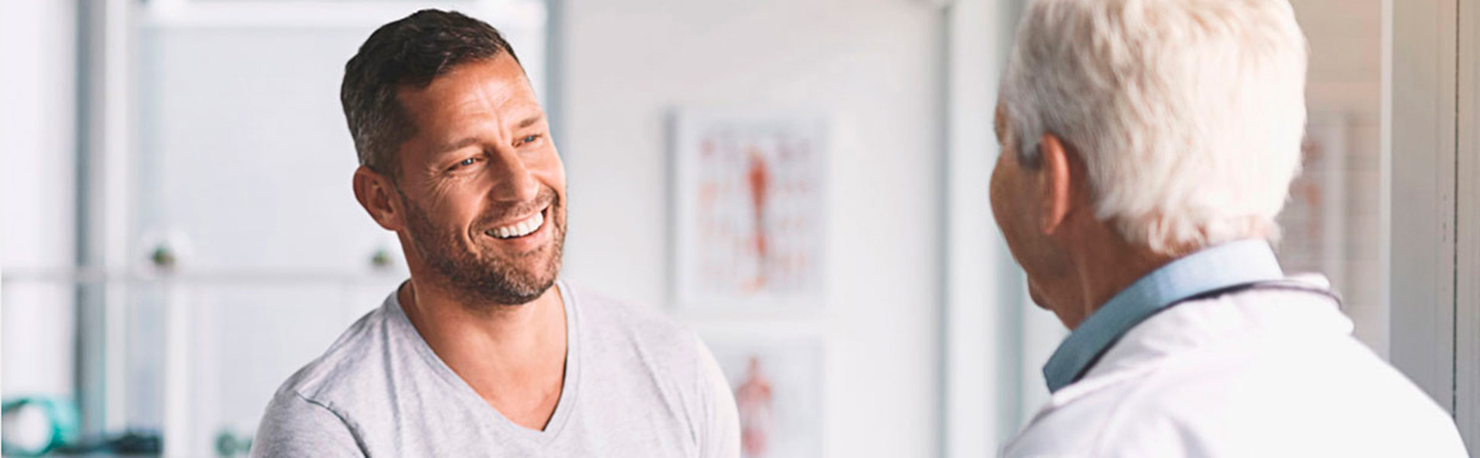 Læge taler med yngre mandlig patient til en konsultation.