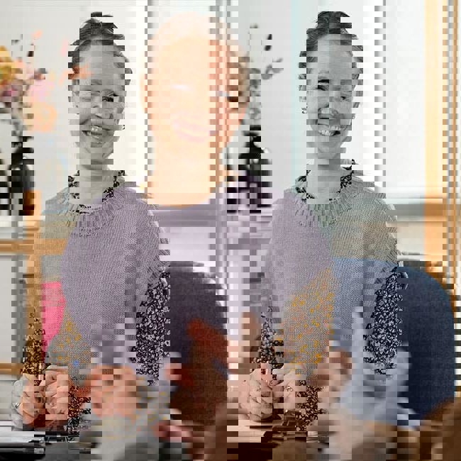 En kvinde sidder smilende og snakker med en mand.