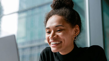 Smilende kvinde har en online samtale på en computer.