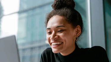 Smilende kvinde har en online samtale på en computer.