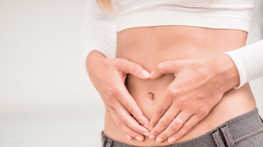Kvinde danner et hjerte med sine hænder over maven.