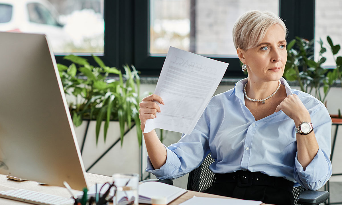 Midaldrende kvinde sidder på et kontor og døjer med hedeture.