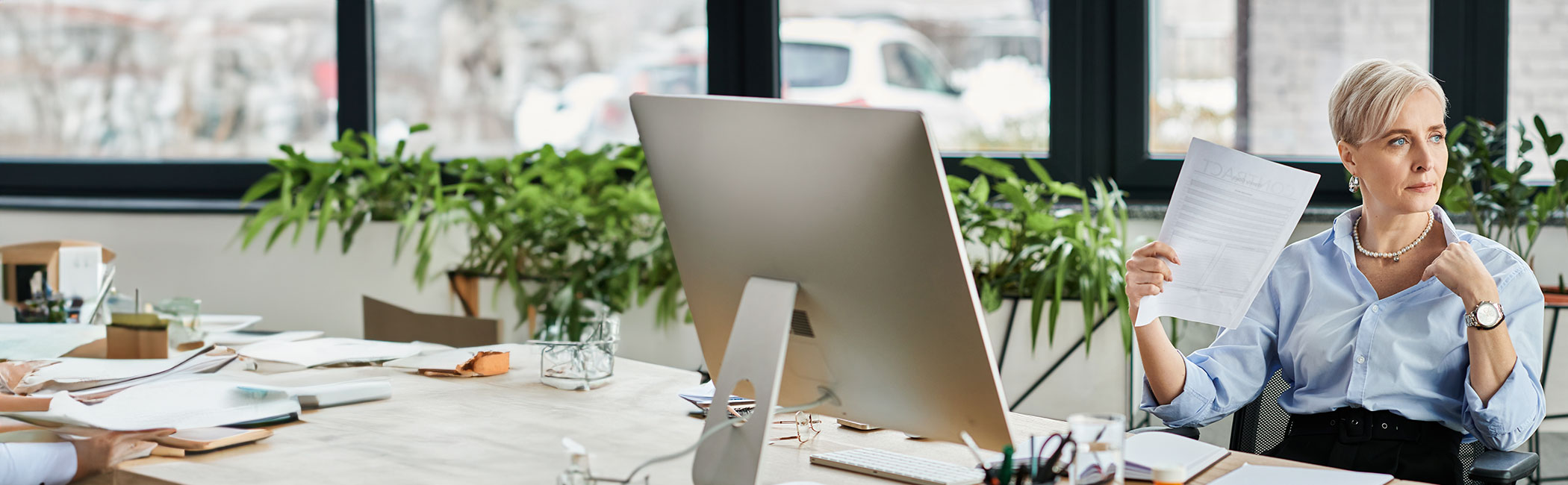 Midaldrende kvinde sidder på et kontor og døjer med hedeture.