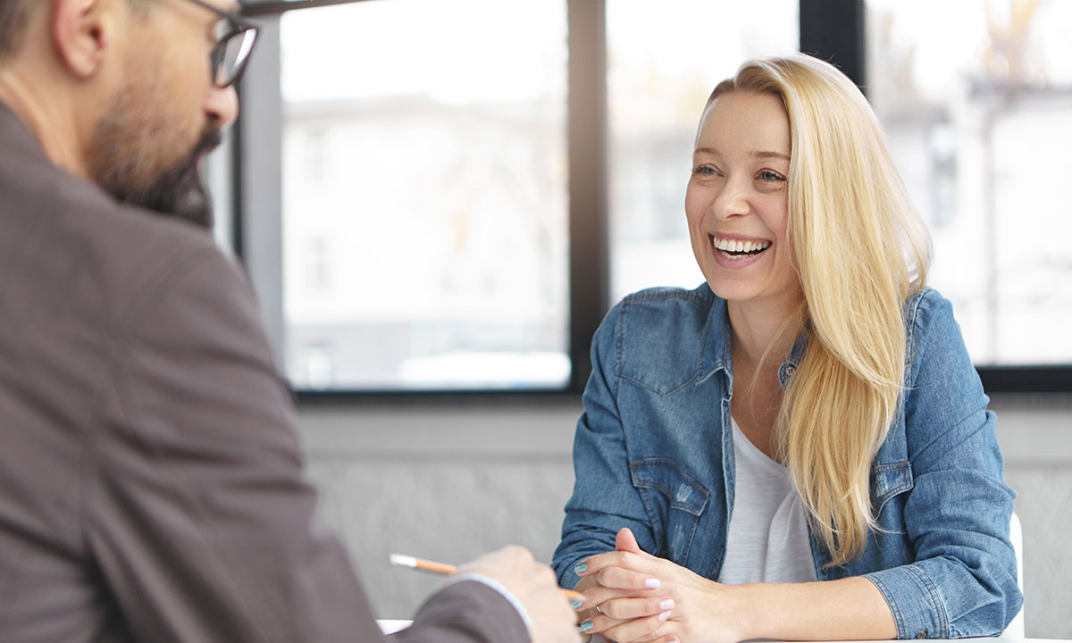 Smilende kvinde sidder til en konsultation hos en erhvervspsykolog.