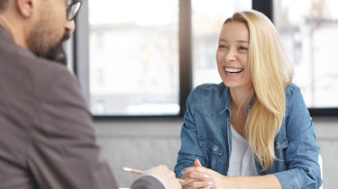 Smilende kvinde sidder til en konsultation hos en erhvervspsykolog.