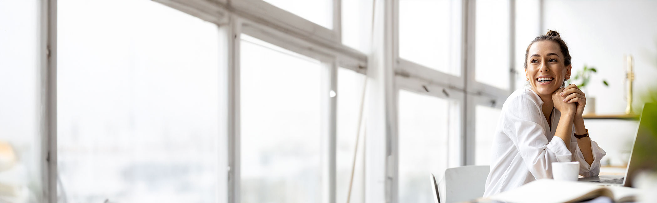 Smilende kvinde ser sig over skulderen og ud af vinduet.