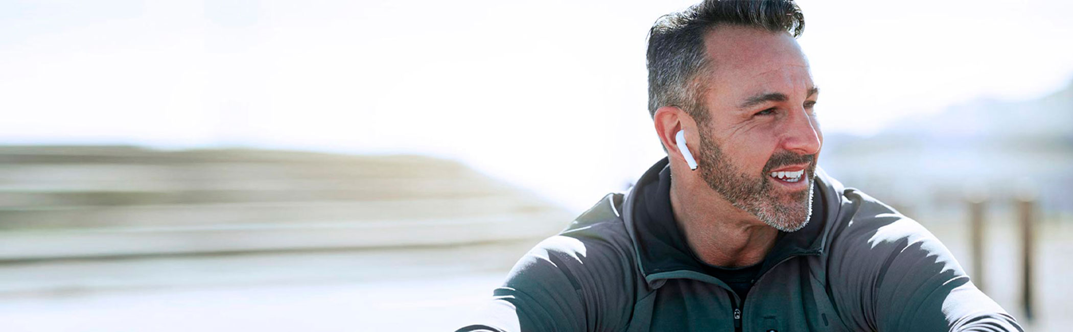 Glad mand sidder i naturen og lytter til musik.