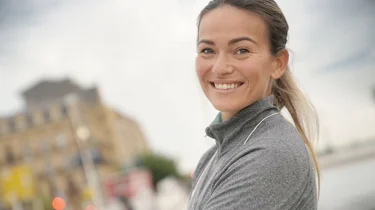 Kvinde i træningstøj smiler til kameraet.