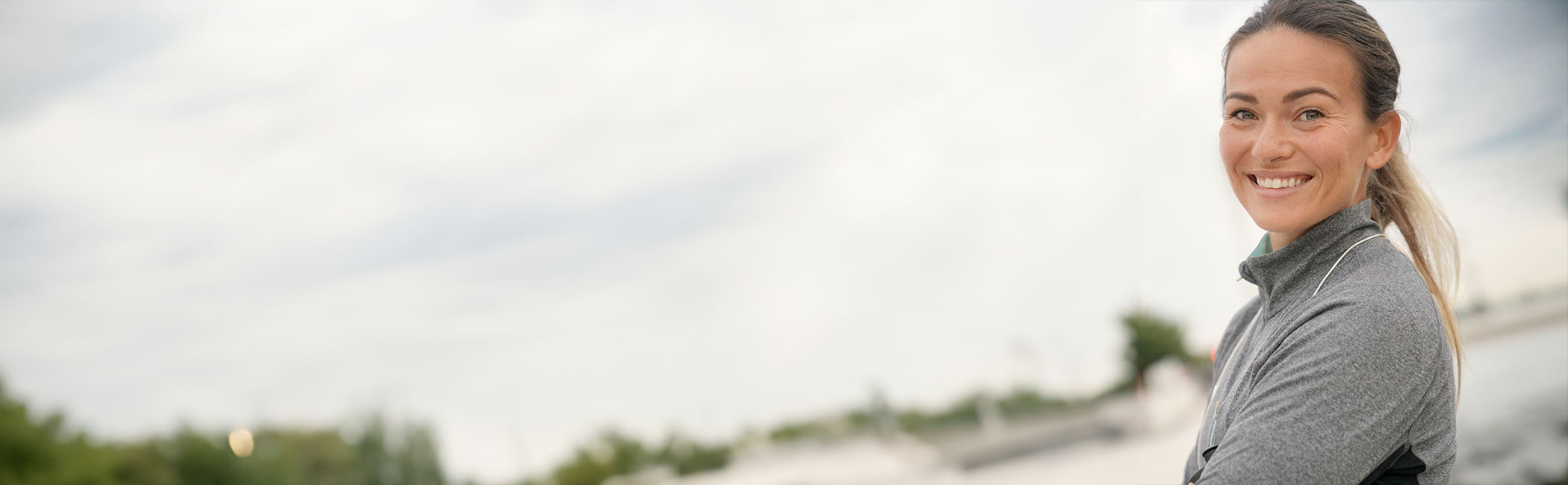 Kvinde i træningstøj smiler til kameraet.