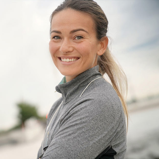 Kvinde i træningstøj smiler til kameraet.