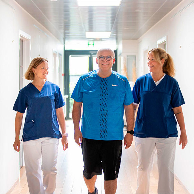 Patient og læger går smilende på et af Aleris hospitaler.