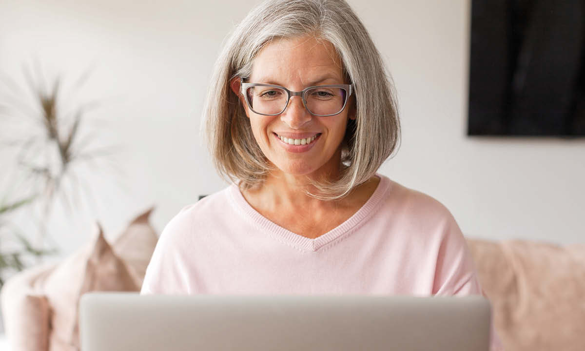 Kvinde sidder smilende ved sin computer.