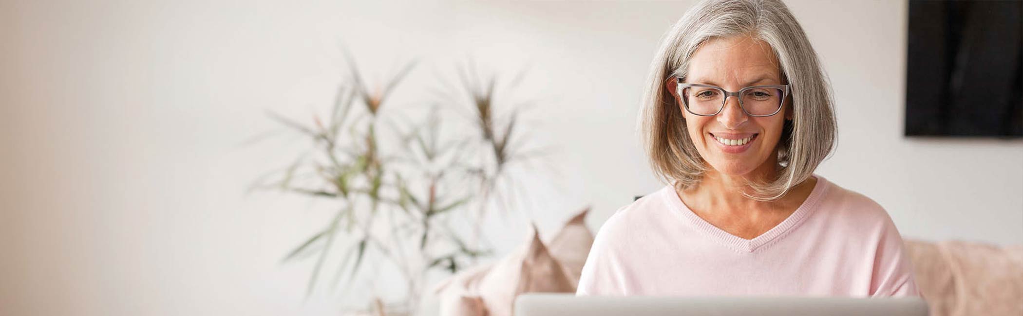 Kvinde sidder smilende ved sin computer.