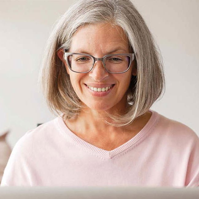 Kvinde sidder smilende ved sin computer.